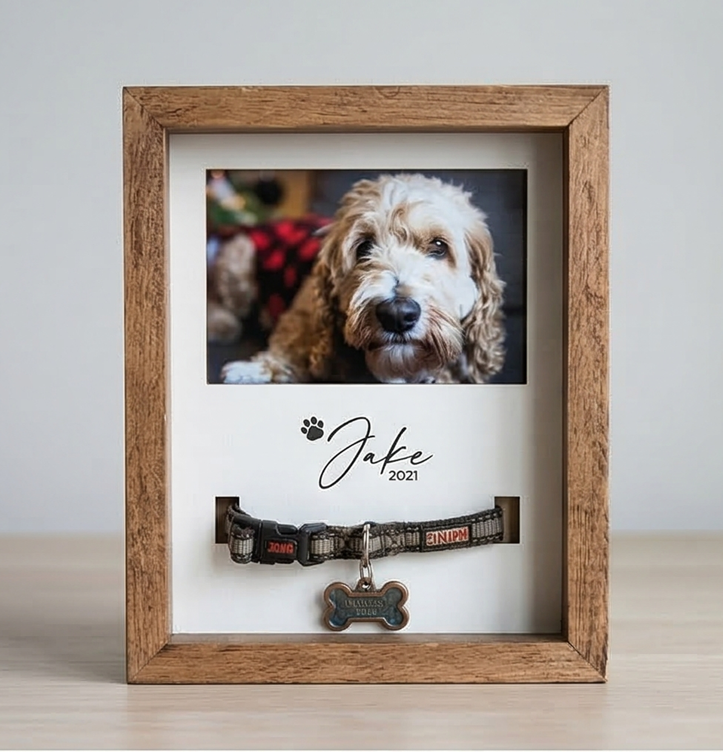 Wooden frame with a photo of a dog and a dog collar with a name tag inside.