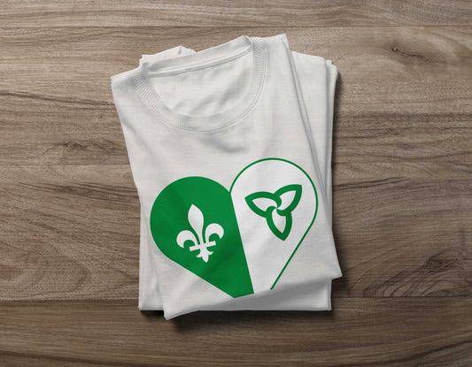 Folded White Franco-Ontarian Heart Flag Shirt on a wooden background, featuring a design of the Franco flag in the shape of a heart.