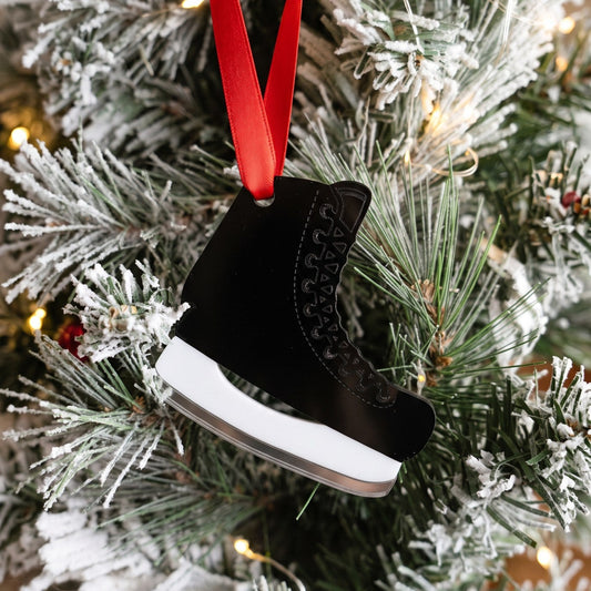 Black and white acrylic hockey skate ornament hanging on a snowy Christmas tree
