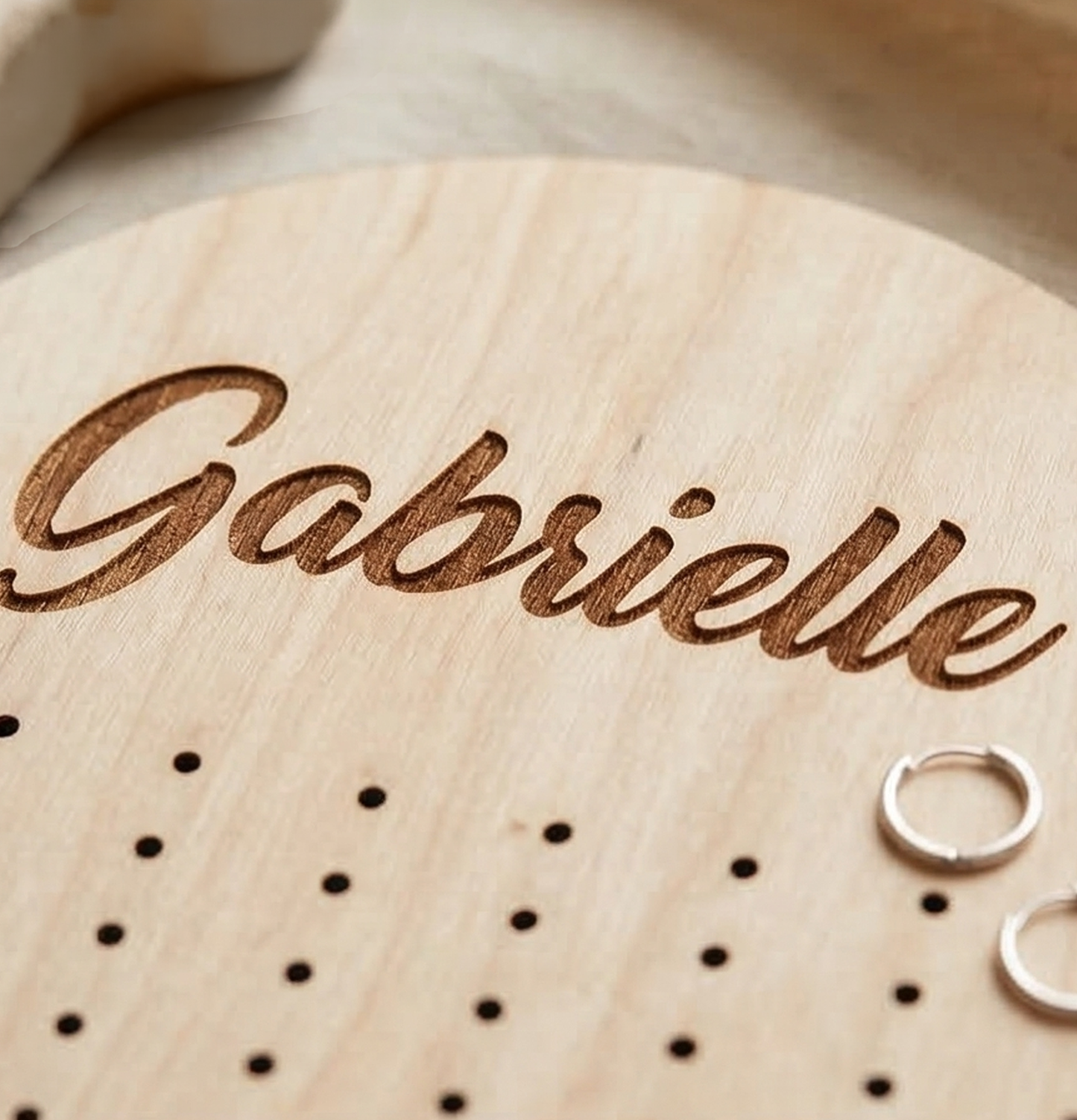 Wooden earring holder with 'Gabrielle' engraved on it, with small small hoop earrings