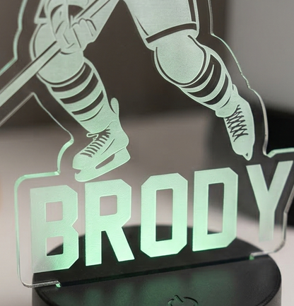 Glowing acrylic plaque with hockey player silhouette and 'Brody' text on a dark background