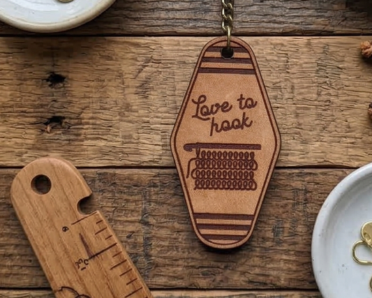 Wooden keychain with 'Love to hook' text on a wooden surface