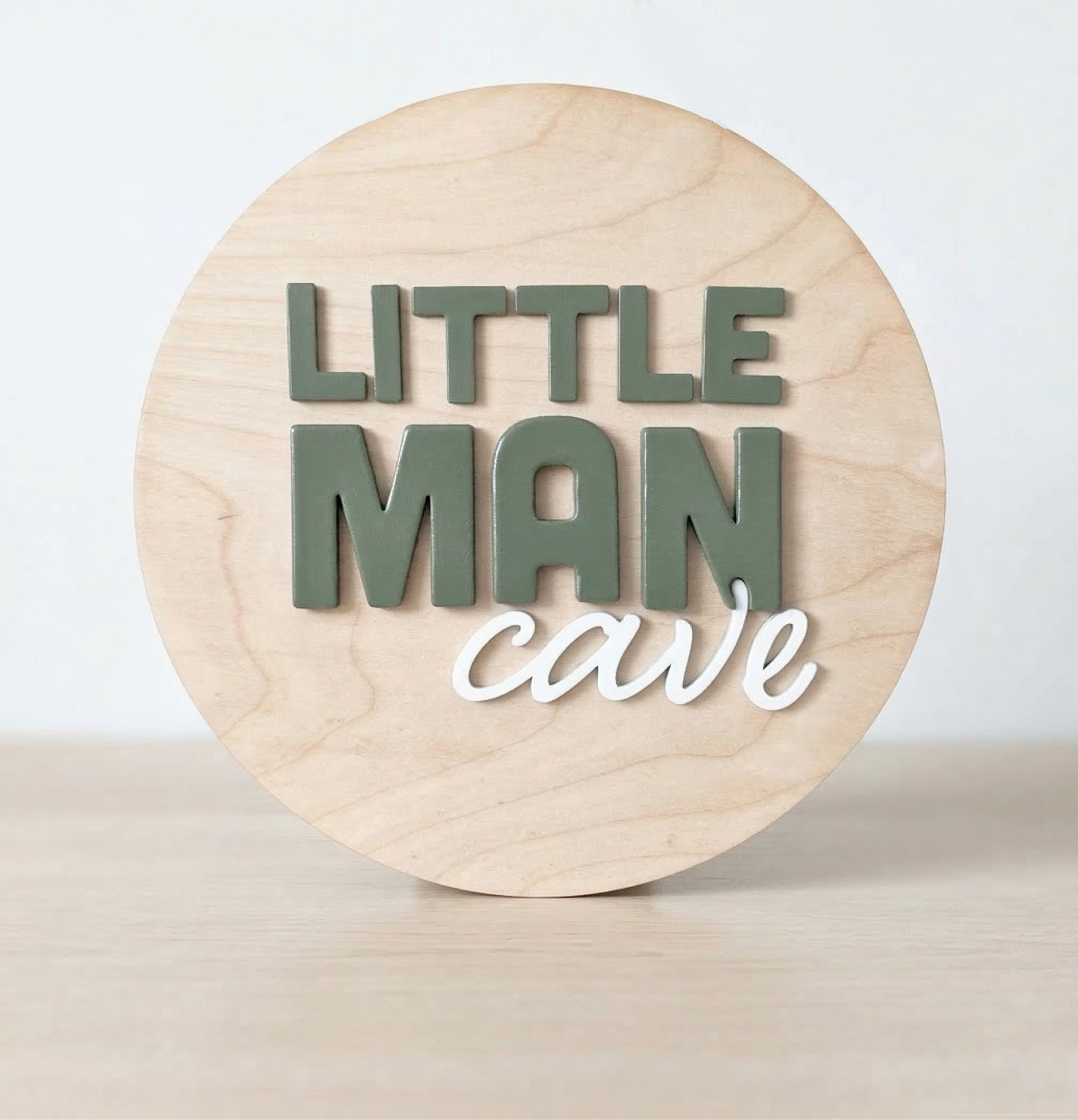 Wooden circular sign with 'LITTLE MAN cave' text on a light wooden background