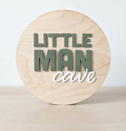Wooden circular sign with 'LITTLE MAN cave' text on a light wooden background