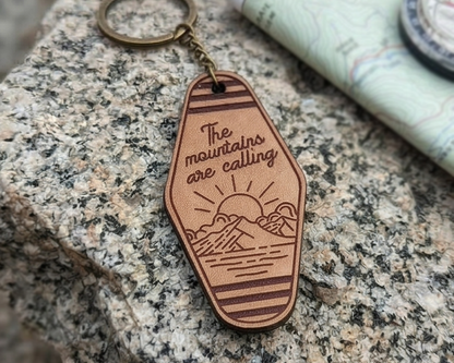 leather keychain with 'The mountains are calling' text on a stone surface