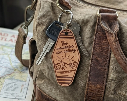 Leather keychain with 'The mountains are calling' text on a backpack