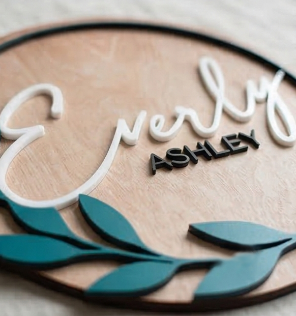 Wooden plaque with 'Everly Ashley' text and teal leaf designs.