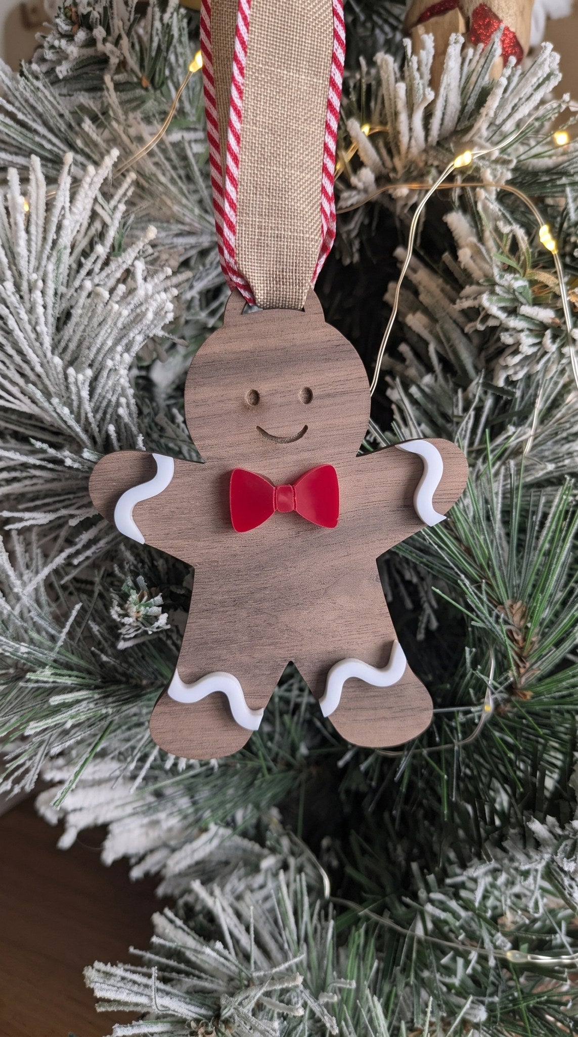 Layered walnut and acrylic gingerbread boy ornament with red bow tie