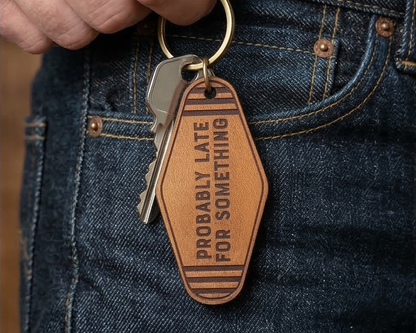leather Keychain tag reading 'Probably Late For Something' attached to a keyring, held against a denim background.
