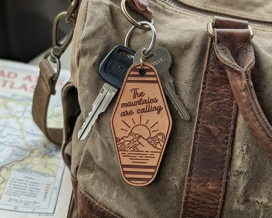 Leather keychain with 'The mountains are calling' text on a backpack