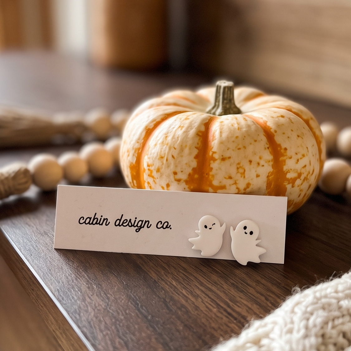 small winking ghost earring leaning on a pumkin