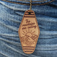Leather Keychain cut and engraved to look like a vintage motel key with The mountains are calling with an illustration of a sun setting over a mountain engraved on it.