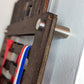 Side view of a dark walnut wooden medal holder highlighting the silver hardware on the wall